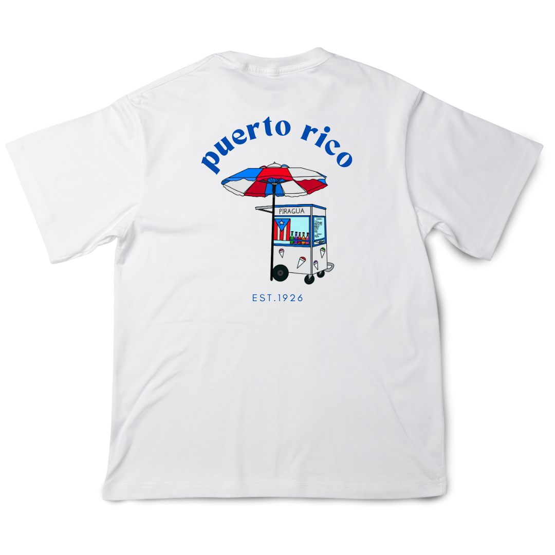 White T-shirt with a colorful design on the back featuring a traditional Puerto Rican piragua cart under a red, white, and blue umbrella. The text above the cart reads 'Puerto Rico' with 'EST. 1926' below